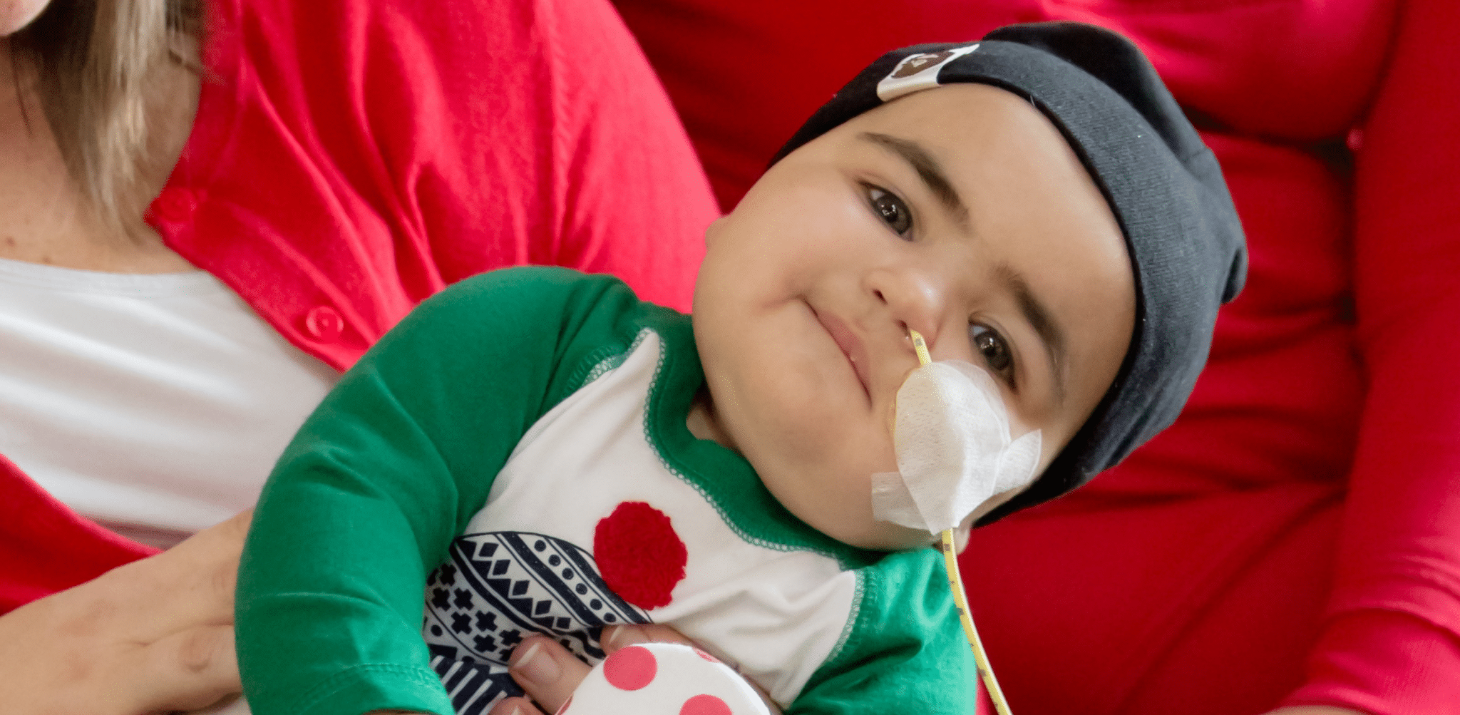 Young child with NG tube smiling, heart sticker holding tube onto face