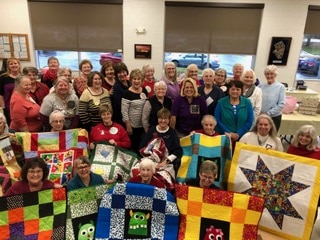 women holding up quilts
