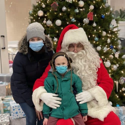 Child sitting on Santa's lap with adult standing