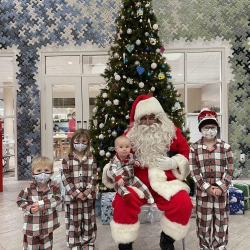 A picture of four children gathered around Santa Claus
