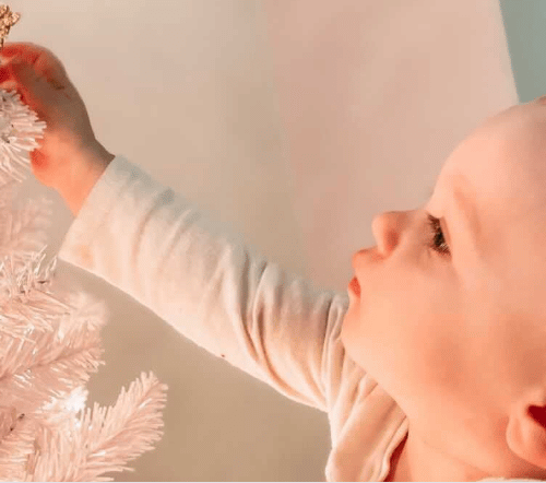 Child touching Christmas tree