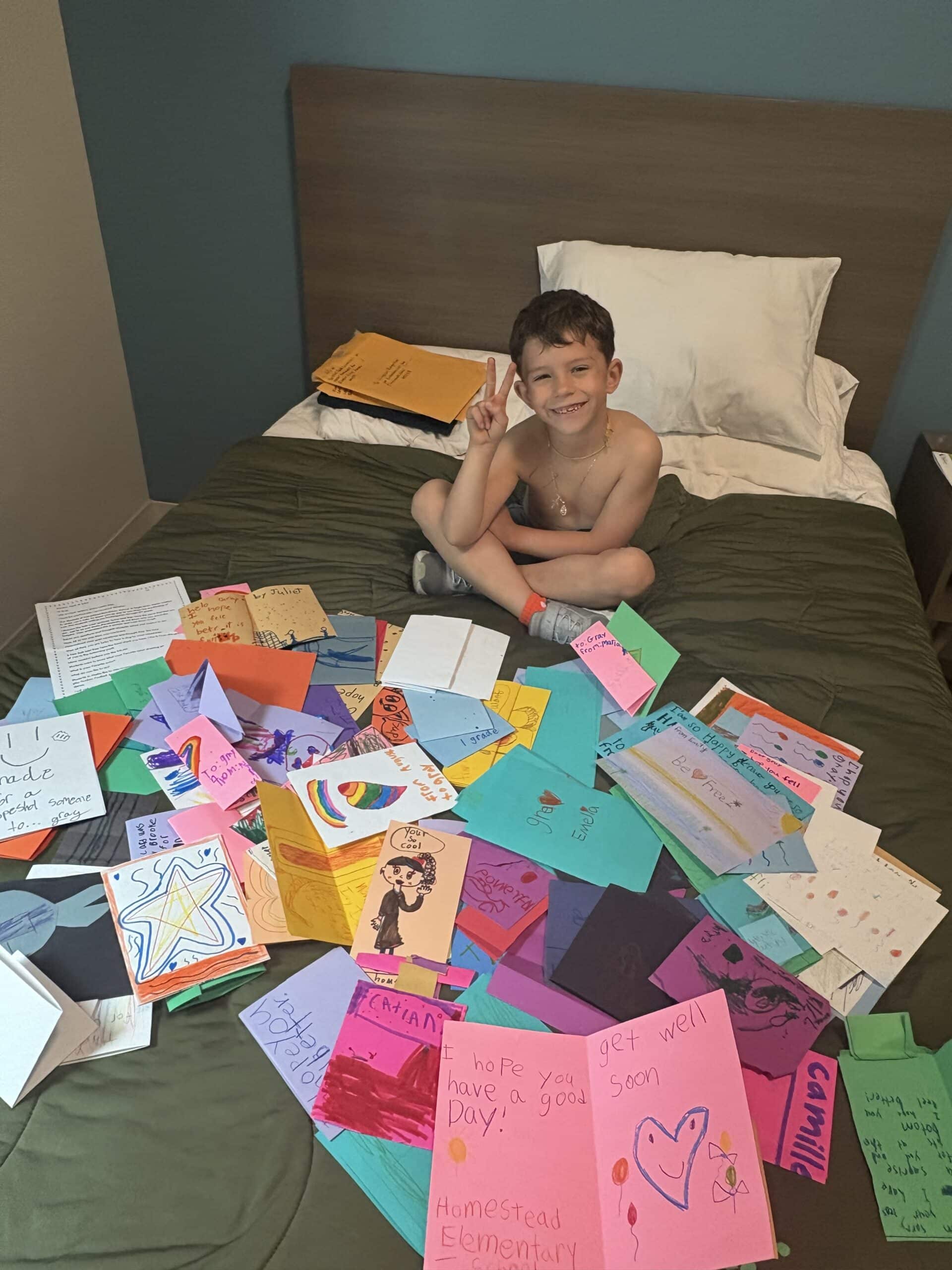 Boy with many cards spread around on a bed.