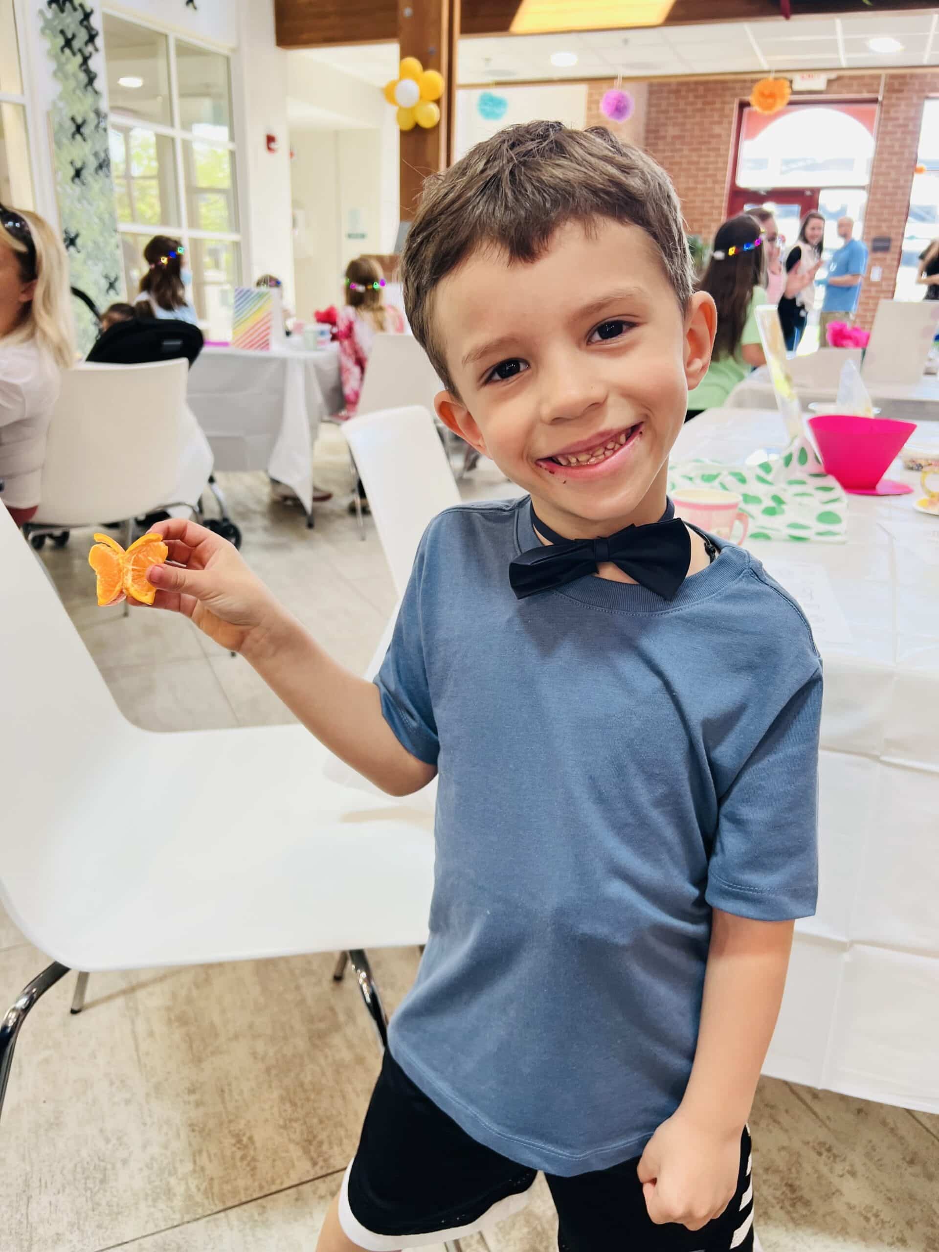 Boy holding orange slices that look like a butterfly