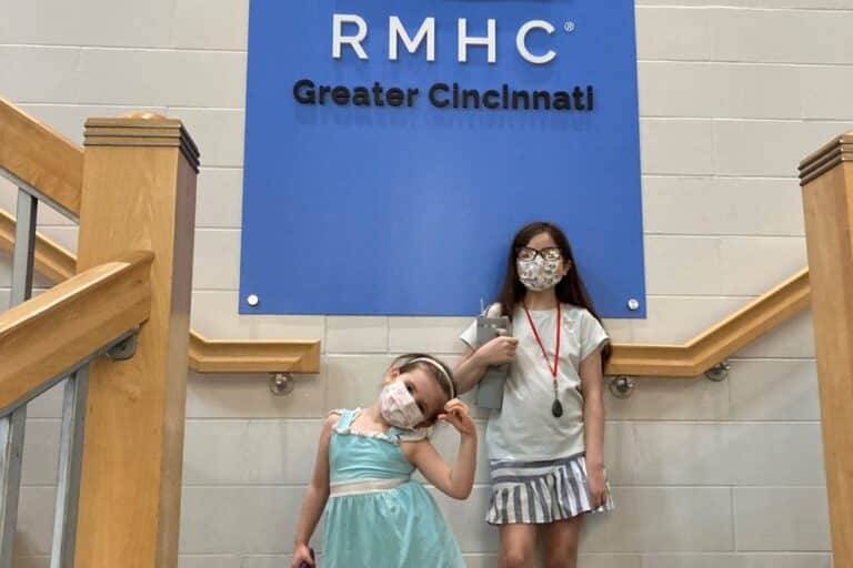 Big and little sister posing for a photo by RMH Cincinnati logo.