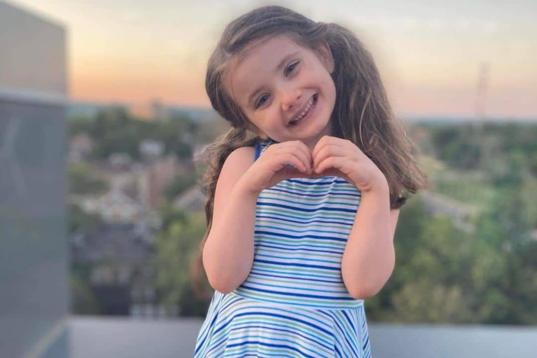Young Addie making a heart with her hands.