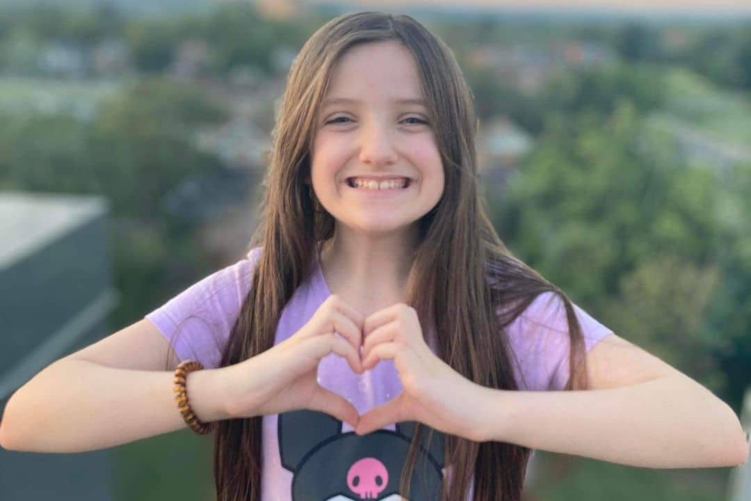 Ava posing with her hands making a heart.