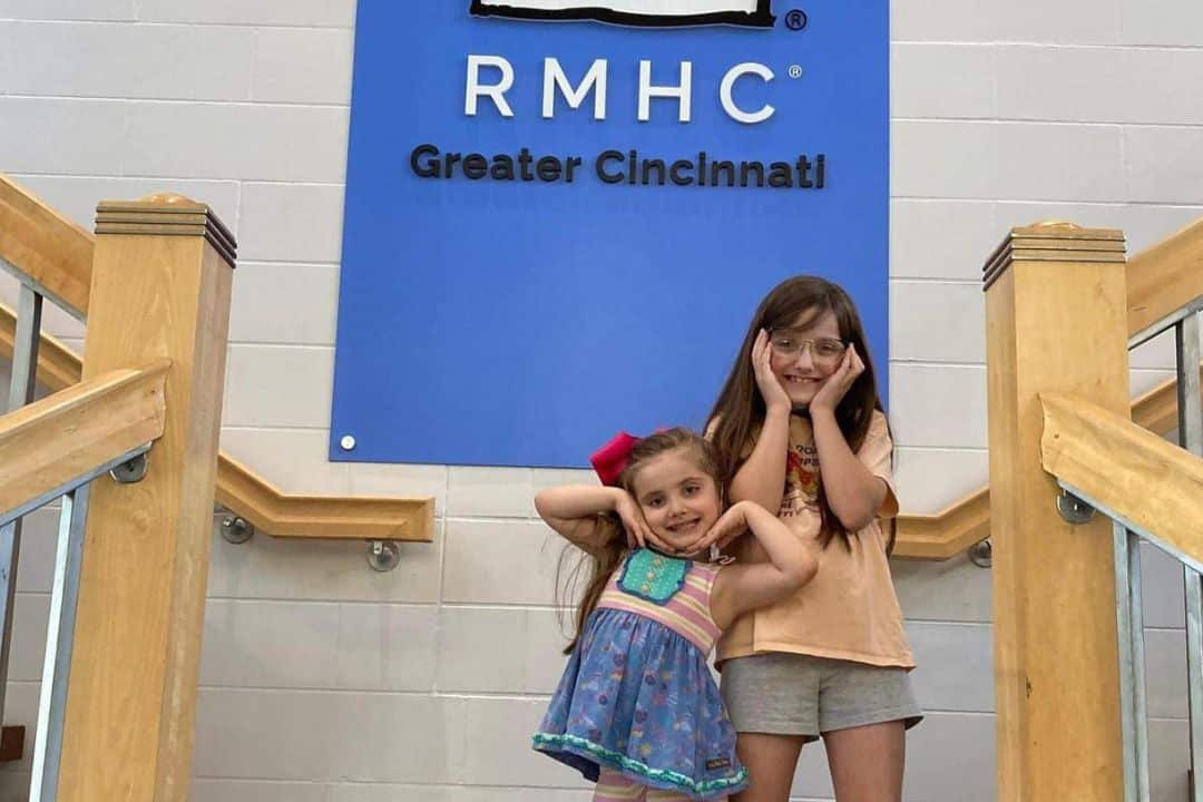 Ava and Addie posing by the RMH Logo sign.